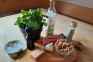 Basilikum in Pflanztopf, Käse, Flasche und Glas mit Pesto