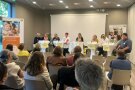 Mehrere Personen stehen hinter fünf Stehtischen 