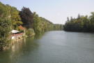 Blick von einer Brücke auf einen Fluss mit bewaldeten Ufern.