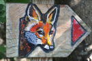 Markierung des Pfades durch Holztafeln mit rotem Pfeil und dem Abbild eines Fuchsgesichts